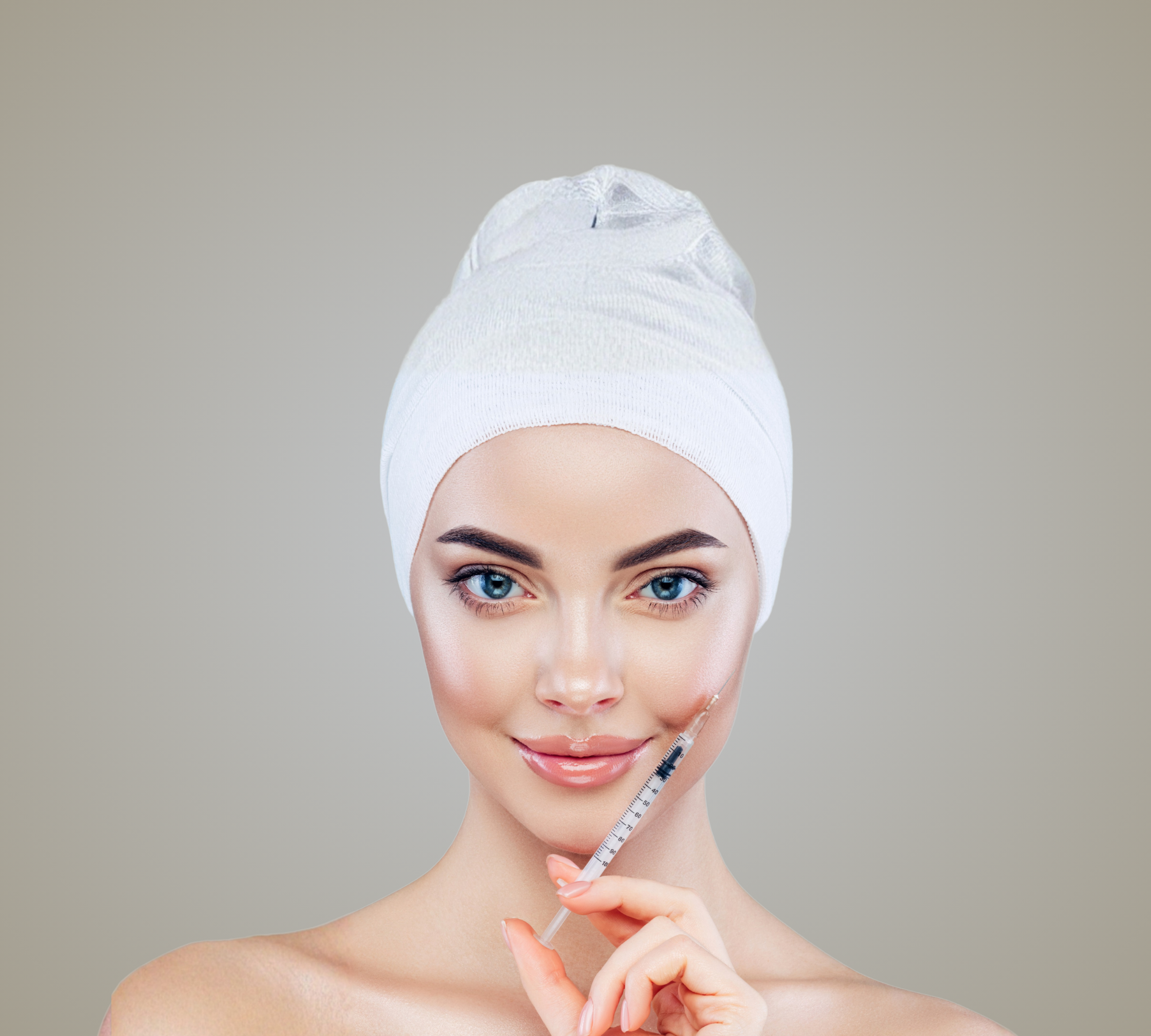 Beautiful woman smiling with injection on her face with a towel on her head against a neutral background. on brand colour of SKN AESTHETICS NZ 